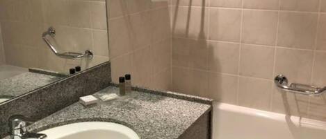 Un baño con lavamanos blanco, un espejo, toallero con toallas dobladas y una bañera.