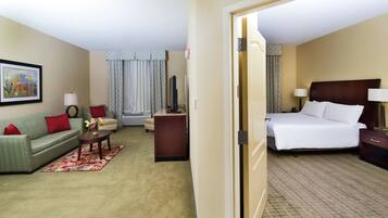 A hotel room with a bed, a sofa, a desk, and a chair.