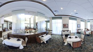 A spacious hotel lobby with multiple dining areas, a reception desk, and large windows allowing natural light. - Hilton Garden Inn Valdosta (Valdosta)