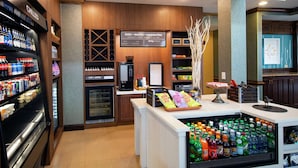 A coffee shop with a variety of beverages, including bottled water, soda, and coffee. There is a refrigerated display case with bottled water and a coffee machine. - Hilton Garden Inn Valdosta (Valdosta)
