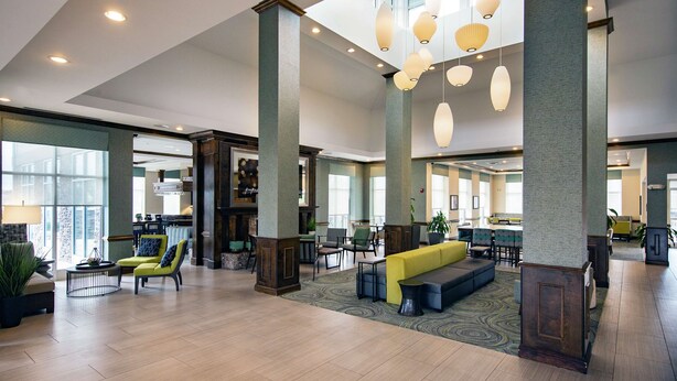 A spacious lobby with high ceilings, large windows, and modern lighting fixtures. - Hilton Garden Inn Valdosta (Valdosta)