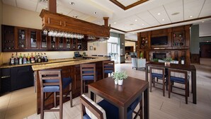 A spacious kitchen with a bar area, wooden cabinets, and a large island with bar stools. - Hilton Garden Inn Valdosta (Valdosta)