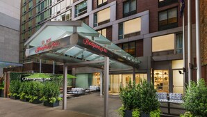 A hotel entrance with a covered walkway, outdoor seating, and a sign for Hampton Inn. - Hampton Inn Manhattan-35th St/Empire State Bldg (New York)