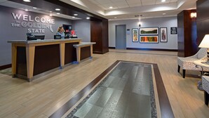 Zona de recepción de un hotel, con mostrador, recepcionista y letrero de bienvenida.