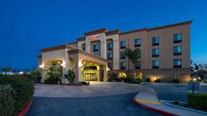 Un hotel Hampton Inn con un diseño moderno, que cuenta con una entrada bien iluminada y un área de estacionamiento.
