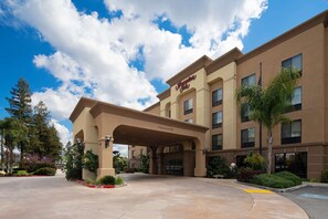 Welcome to Hampton Inn, where guests can enjoy a convenient entrance under a covered area, surrounded by beautifully landscaped gardens and a paved walkway.