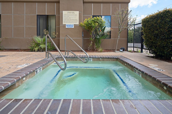 Una piscina con una escalera metálica, rodeada por un suelo de ladrillo.