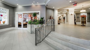 Een ruime lobby met een trap, een receptiebalie en een groot raam met decoratieve objecten.
