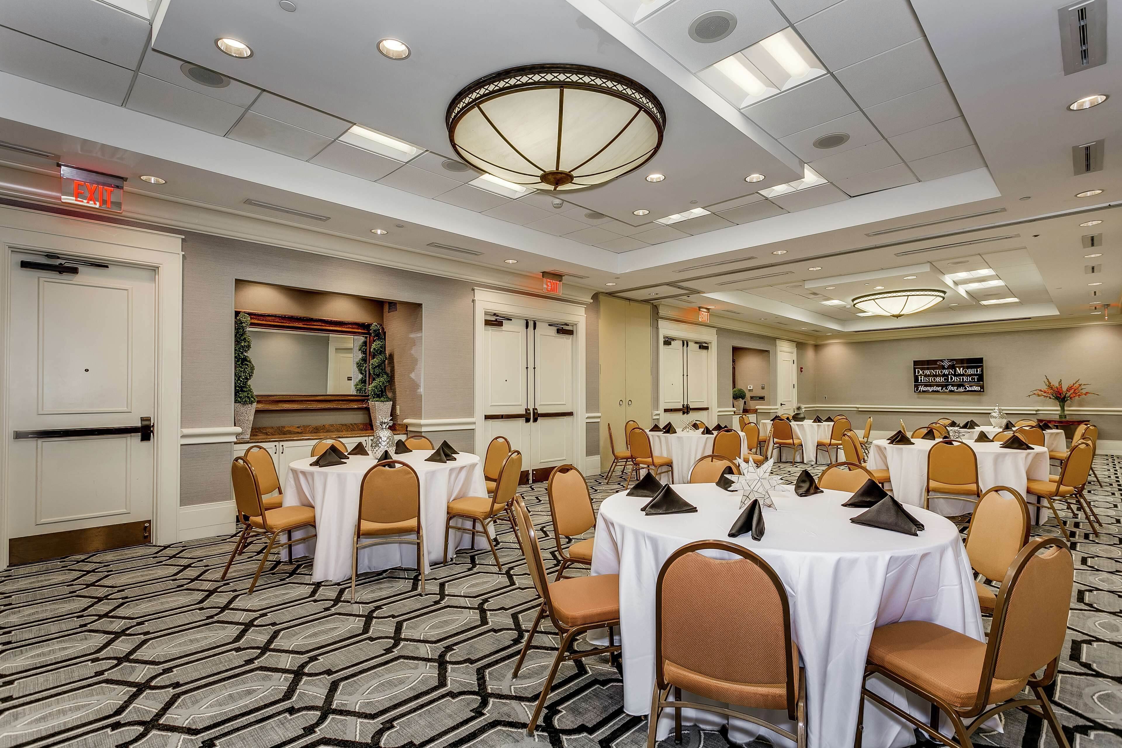 A conference room with round tables, chairs, and a patterned carpet.