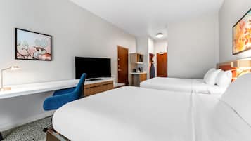 A hotel room with a bed, a desk, a chair, a television, and artwork on the walls.