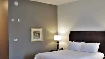 A hotel room with a bed, a nightstand, a lamp, and a framed picture on the wall.