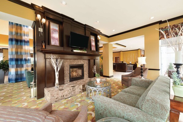 A spacious living area with a fireplace, comfortable seating, and a television. - Hilton Garden Inn Warner Robins (Warner Robins)