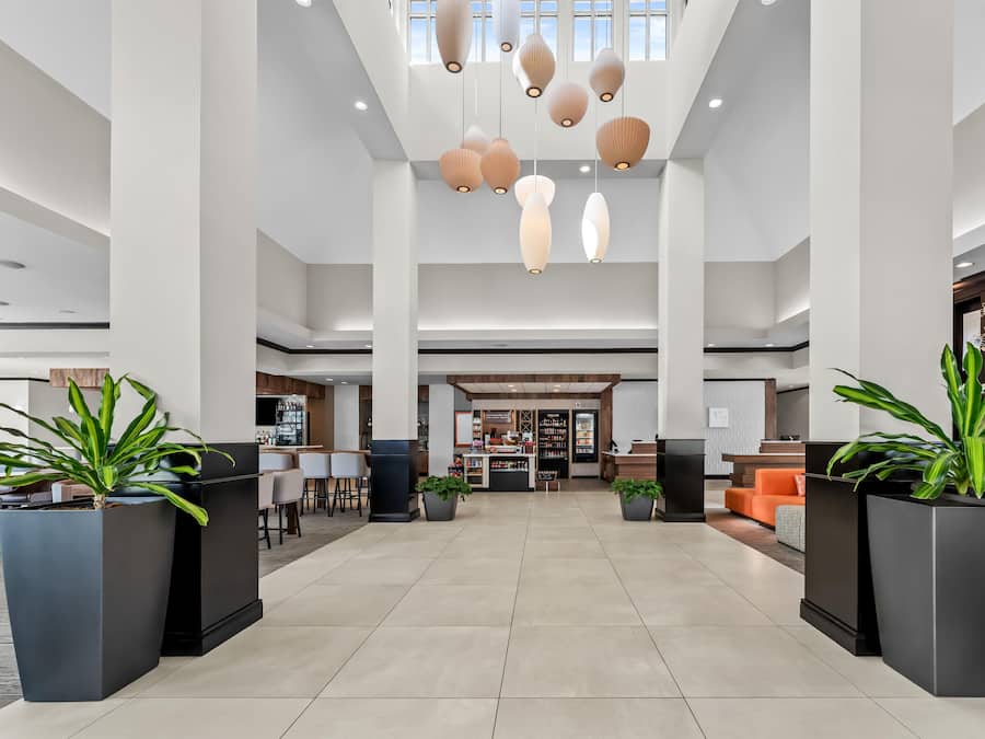 Un vestíbul ample amb un sostre alt, il·luminació penjant moderna i una recepció central.