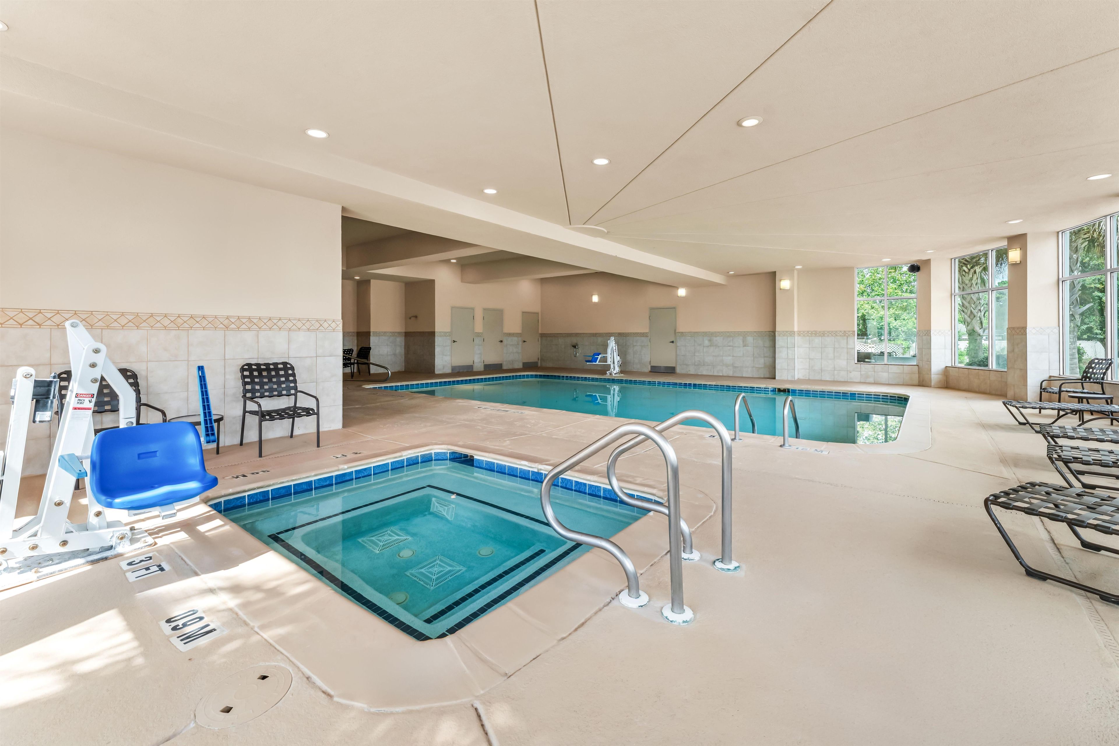 An indoor swimming pool with multiple lanes, safety railings, and a changing room area.