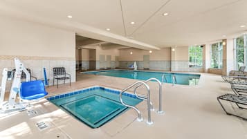 An indoor swimming pool with multiple lanes, safety railings, and a changing room area.