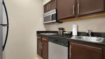 A kitchen with dark brown cabinets, a stainless steel microwave, a dishwasher, and a sink with a faucet.