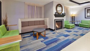 A modern living room with a beige sofa, green armchairs, a round coffee table, and a patterned carpet. - Holiday Inn Express & Suites Warminster - Horsham by IHG (Warminster)