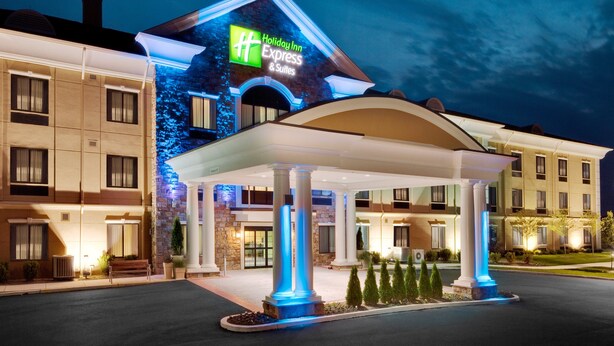A Holiday Inn Express & Suites building with a well-lit entrance and a covered outdoor area with columns. - Holiday Inn Express & Suites Warminster - Horsham by IHG (Warminster)