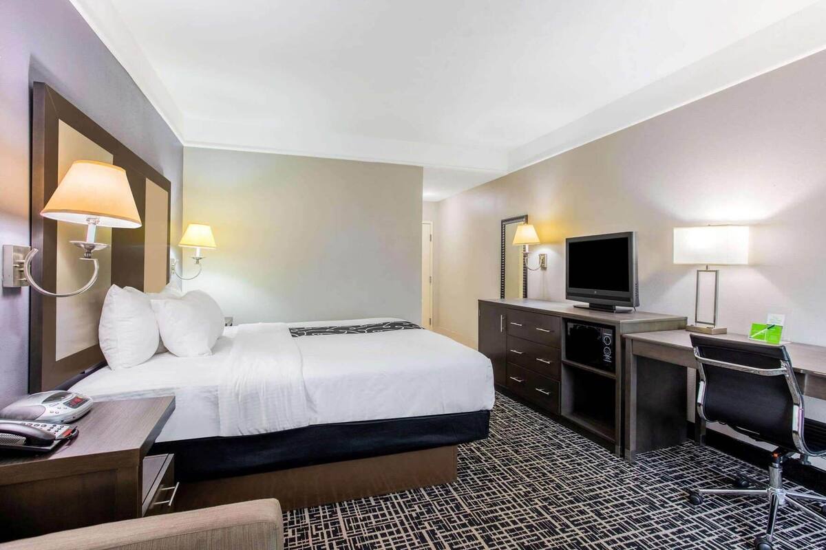 Ein Hotelzimmer mit Bett, Schreibtisch, Fernseher und zwei Wandleuchten.