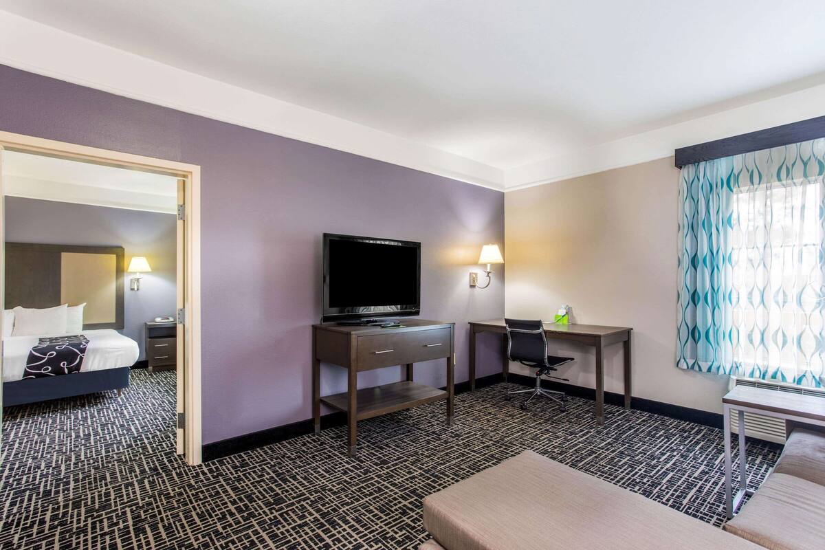 Ein Hotelzimmer mit Bett, Schreibtisch, Fernseher und einem Fenster mit Vorhängen.