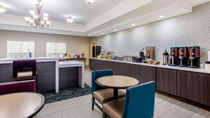 Un moderno hall de hotel con una zona de estar central, una kitchenette y una estación de café.