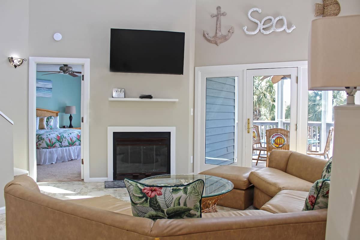 A living room with a TV, fireplace, and a view of the outside.