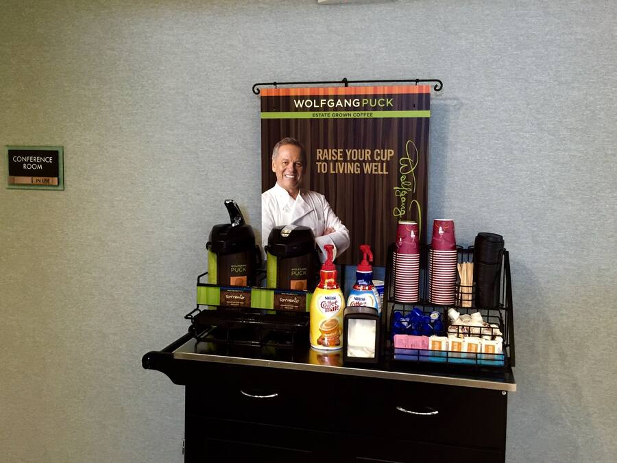 A coffee station with coffee makers, cups, and condiments.