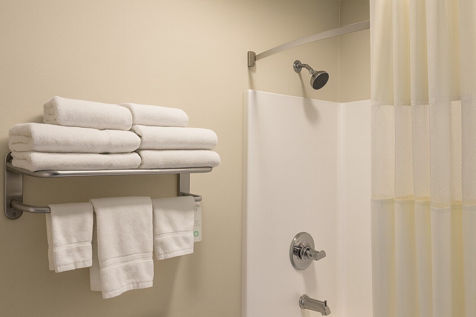 A bathroom with a shower, a towel rack with folded towels, and a shower control panel.