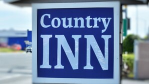 Placa de A Country Inn com fundo azul e letras brancas.