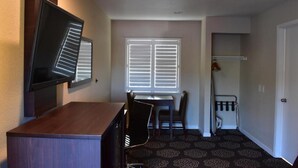 A compact room with a desk, chair, and a television mounted on the wall.