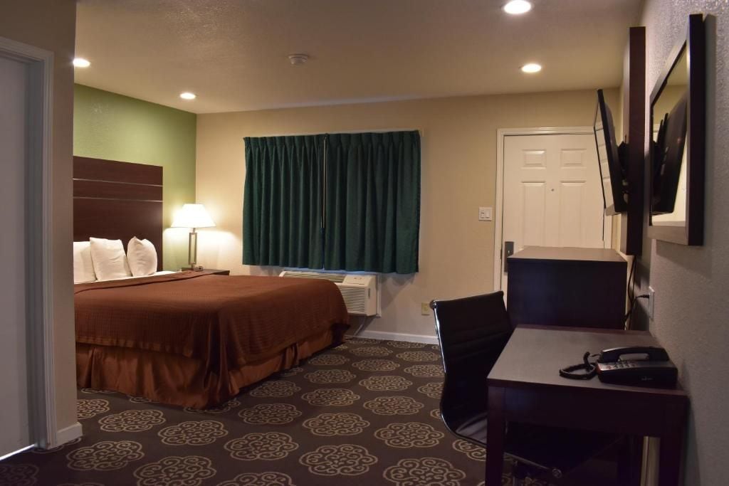Een hotelkamer met een bed, een bureau, een stoel, een televisie en een deur.