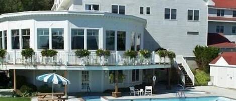 A large, two-story building with a balcony and a swimming pool.
