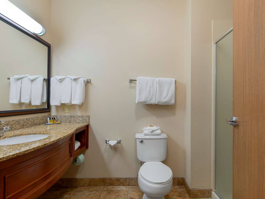 Een badkamer met een wastafel, spiegel, toilet en handdoekhouder.
