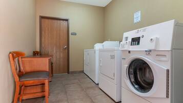 A laundry room with a wooden chair, a washing machine, and a dryer.