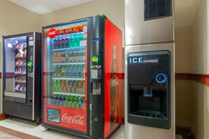 Una hilera de máquinas expendedoras, incluyendo un refrigerador de Coca-Cola y un dispensador de Coca-Cola.