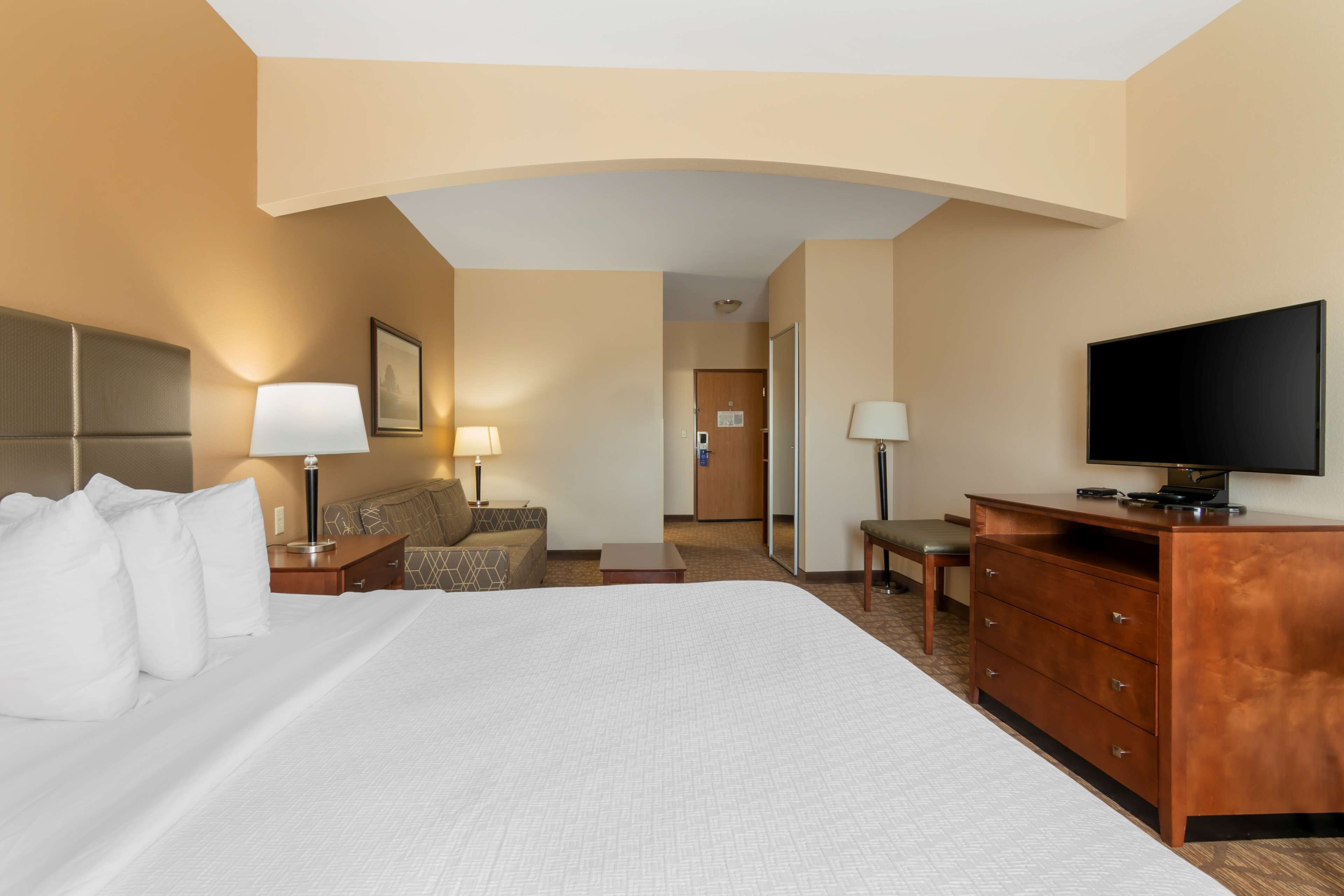 A hotel room with a large bed, a television, a desk, and a chair.