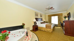 A hotel room with a large bathtub, a bed with a headboard, a desk, and a ceiling fan. - Best Western Lone Star Inn (Edna)