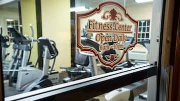 A fitness center sign with the text "Open Daily 6am-10pm" and a reflection of exercise equipment.