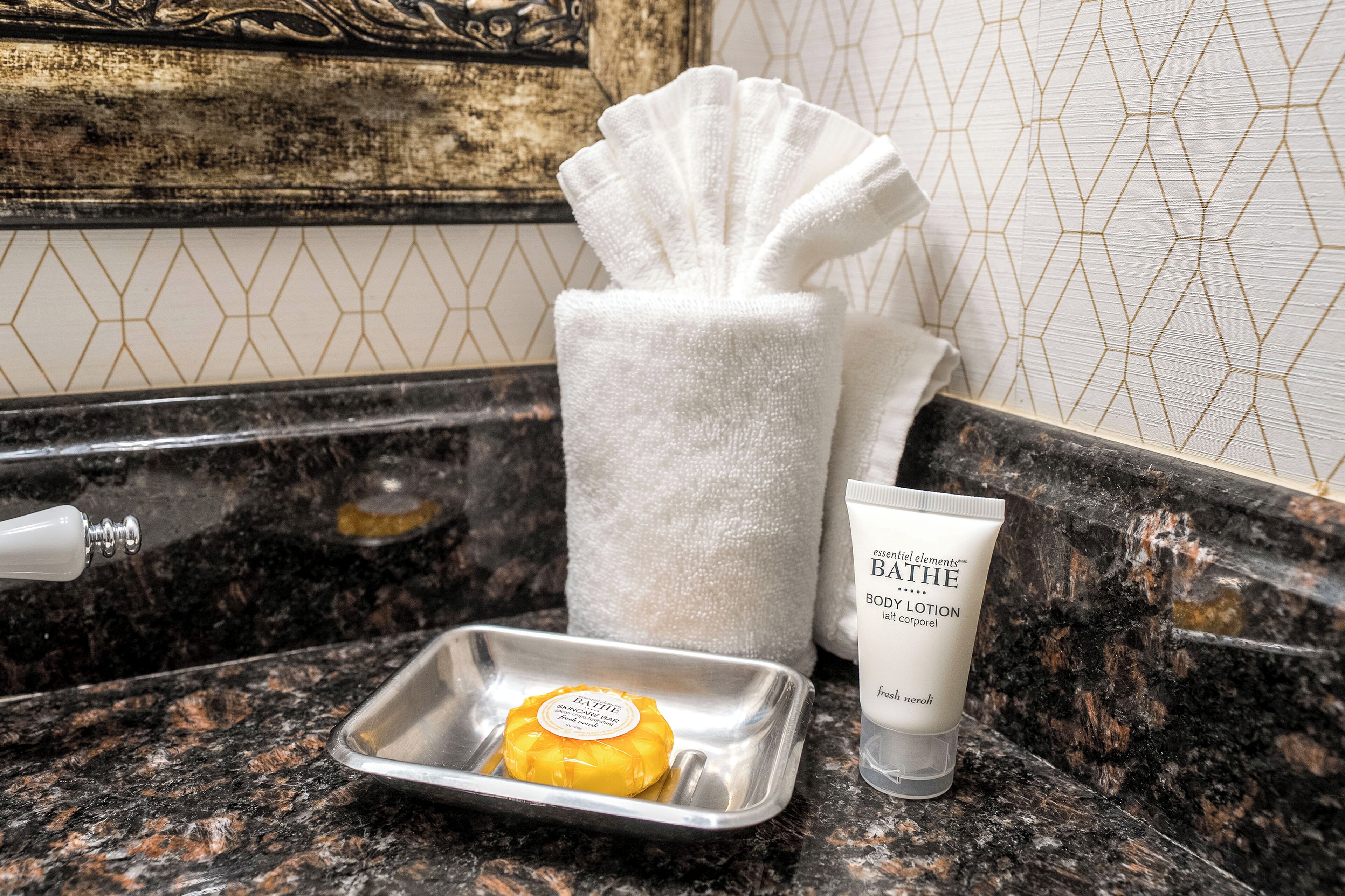 A bathroom counter with a soap bar, a towel, and a lotion tube.