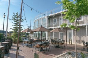 An outdoor patio with tables and chairs, surrounded by a white building with balconies.