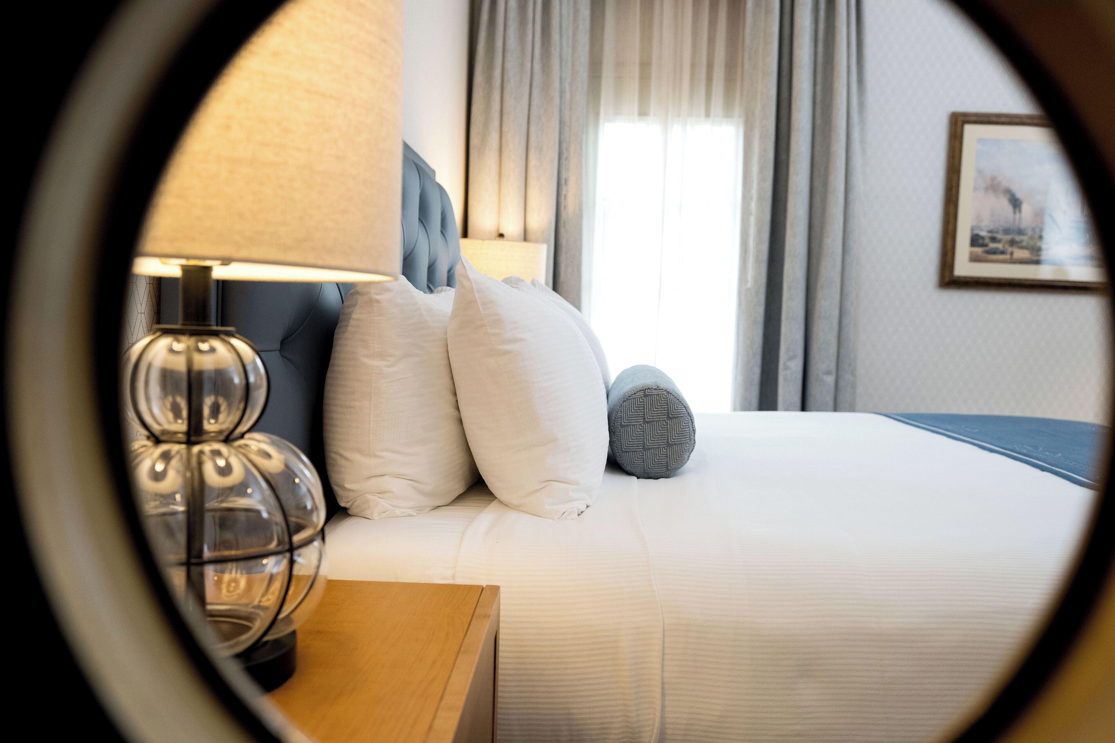 Een hotelkamer met een bed, een lamp en een raam met gordijnen.