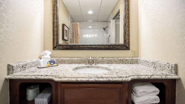 A bathroom with a marble sink, wooden vanity, and a large mirror.