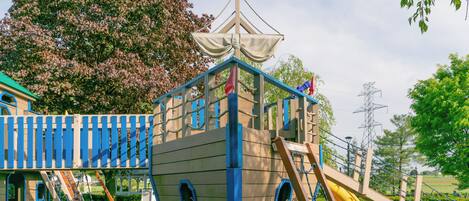 A playground with a ship-themed play structure, including slides and climbing areas.