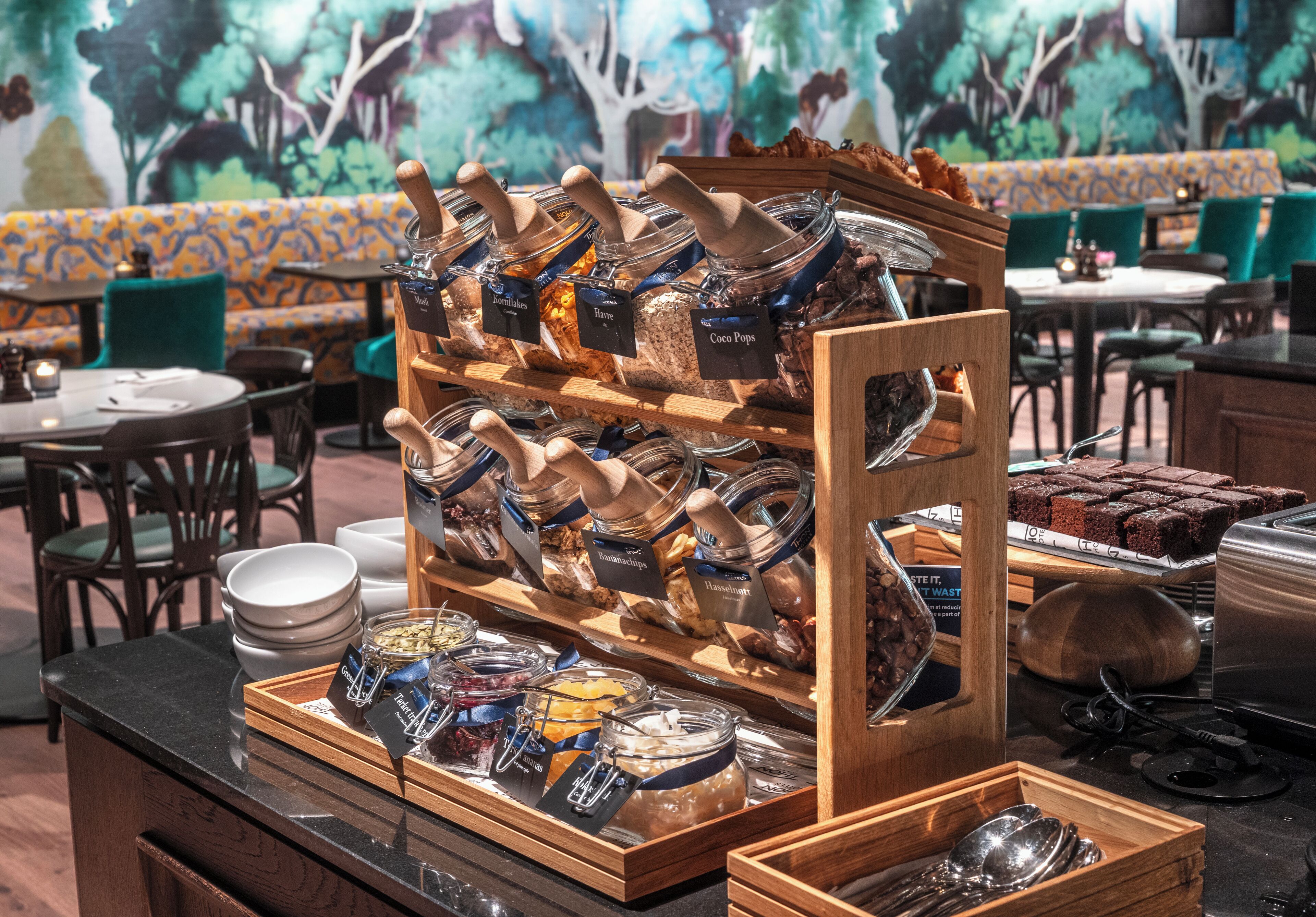 A buffet area with various food items in glass containers, wooden serving boards, and a seating area with patterned cushions.