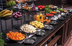 Un bufé con diversas frutas, verduras y bebidas.