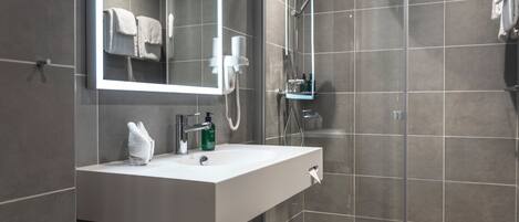 A modern bathroom with a white sink, a mirror, and a shower area.