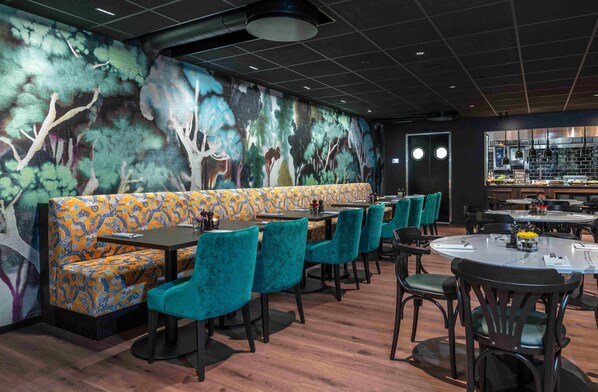Un restaurante con asientos estampados, un mural y una zona de bar.