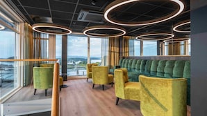 A modern lounge area with circular light fixtures, comfortable seating, and large windows offering a view of the city. - Thon Hotel Panorama (Oslo)