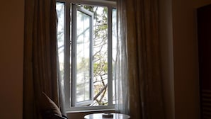 A room with a window, a round table, and a chair. - Silicrest Hotel (Bengaluru)