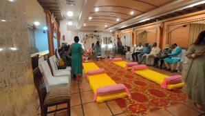 A room with tiered seating, a stage, and a floral arch. - Silicrest Hotel (Bengaluru)